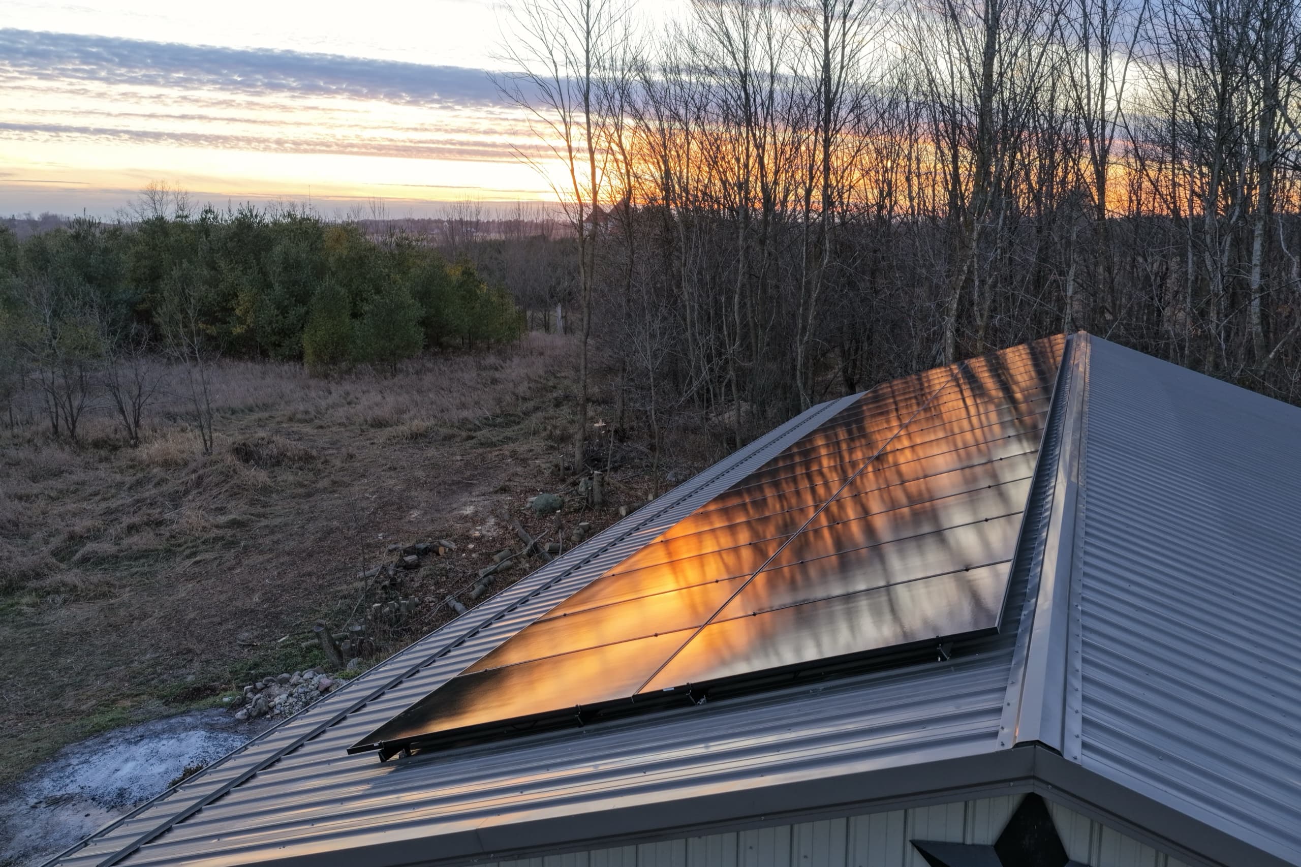 All-black solar array on a standing seam metal roof at sunset in Denmark, Wisconsin