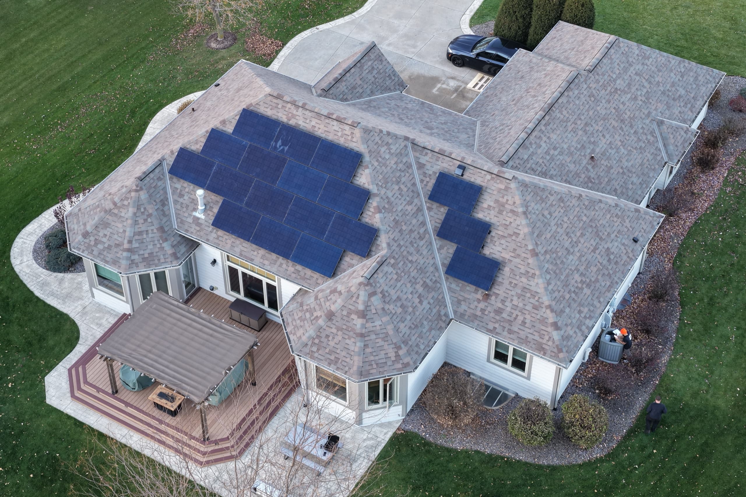 Drone view of the all-black solar array across two roof faces of a Muskego, Wisconsin home