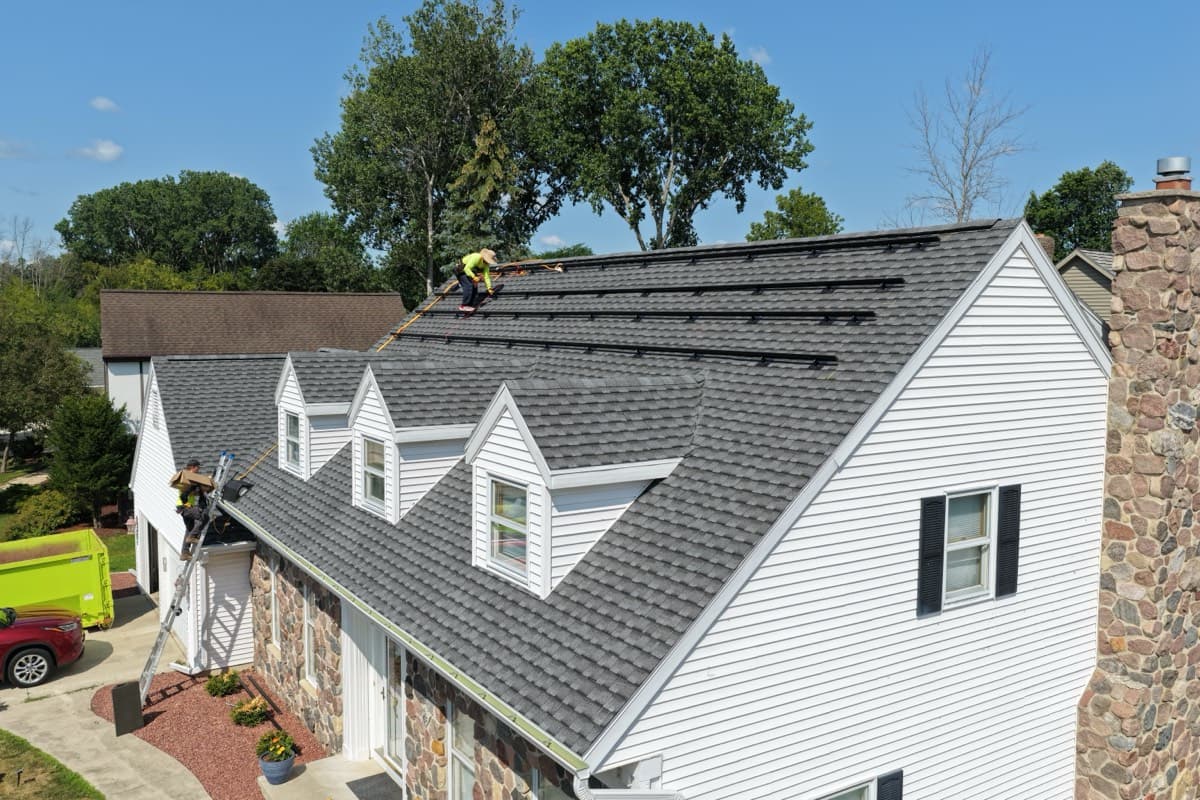 Sevens Solar crew setting all-black mounting rails and under-shingle flashings on a Manitowoc, Wisconsin roof before the panels go on